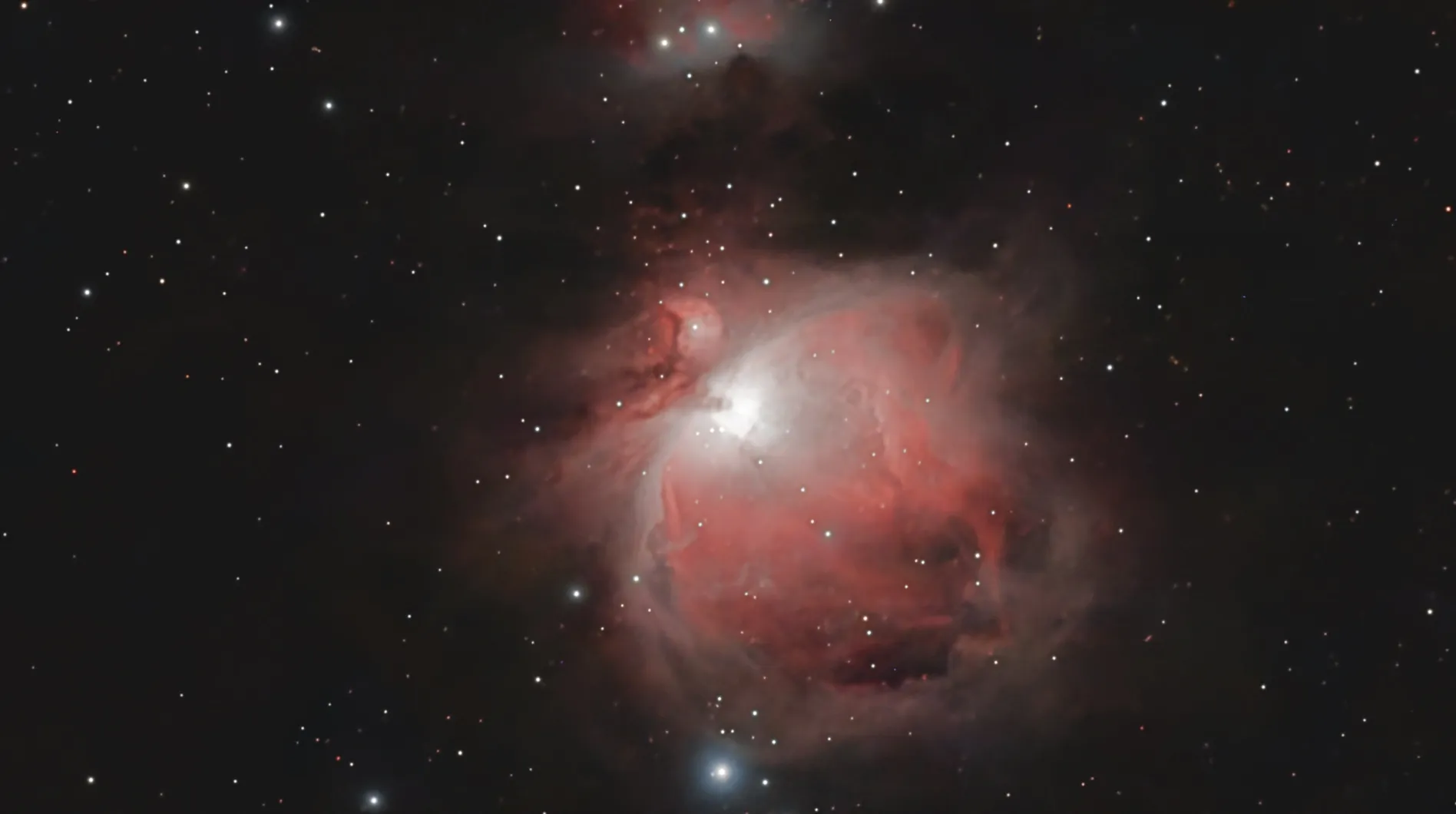 The Orion Nebula: a glowing red and white cloud of gas with a bright core, surrounded by stars, with the Running Man Nebula at the top edge.